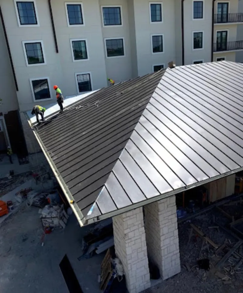 Crew installing standing seam metal roof panels on a commercial project in Corbin